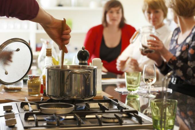 Η ανάδευση μιας κατσαρόλας σε μια κουζίνα σε ένα νησί κουζίνας επιτρέπει την αλληλεπίδραση με τους επισκέπτες του δείπνου.