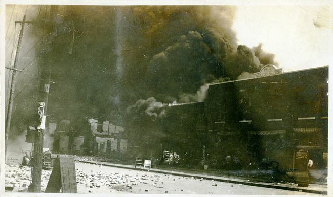Κατεστραμμένες ιδιοκτησίες και καπνός που προέρχεται από κτίρια μετά τη σφαγή του αγώνα της Tulsa, Tulsa, Οκλαχόμα, Ιούνιος 1921.