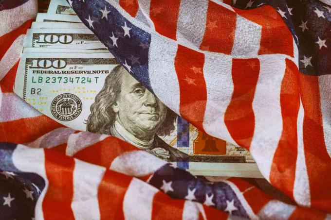 Η σημαία των ΗΠΑ τυλίγεται γύρω από χαρτονομίσματα εκατό δολαρίων.