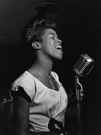 Sarah Vaughan τραγουδώντας σε ένα μικρόφωνο, ασπρόμαυρη φωτογραφία.