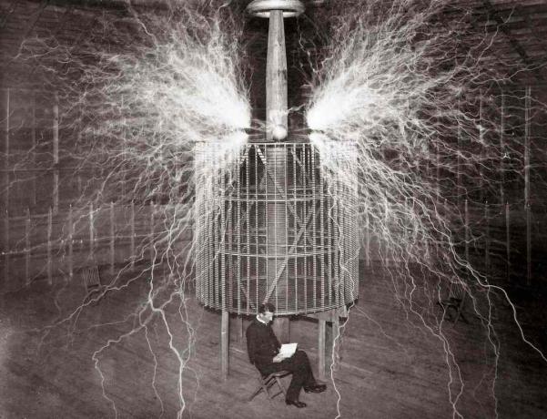 Ο Nikola Tesla κάθεται στο εργαστήριο του στο Colorado Springs δίπλα στο τεράστιο του 
