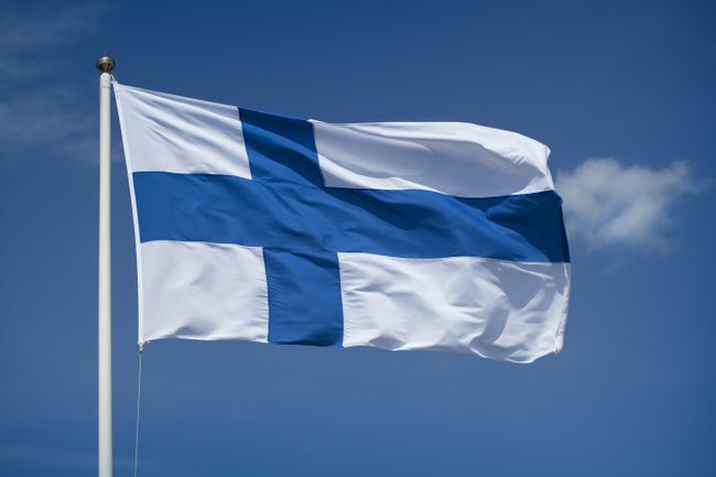 Υψωμένη φινλανδική σημαία με φόντο μπλε του ουρανού